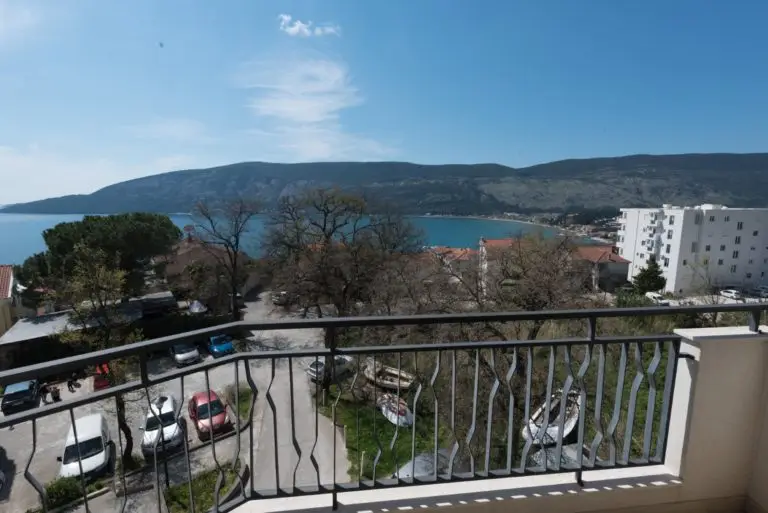 Balcony view of sea, bay, mountains, and parked cars