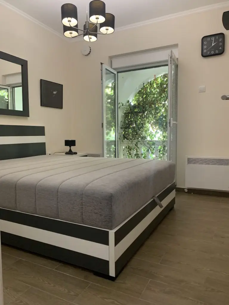 Bedroom with striped bed, open window, and wall clock