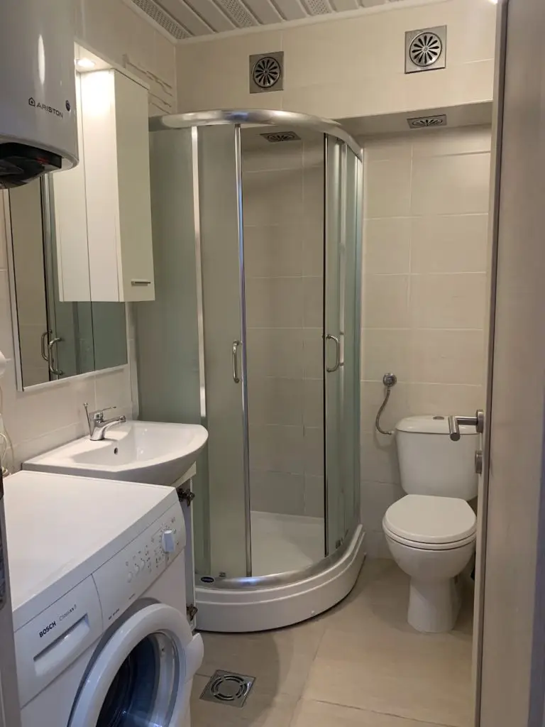 Small bathroom with shower, sink, toilet, and washing machine