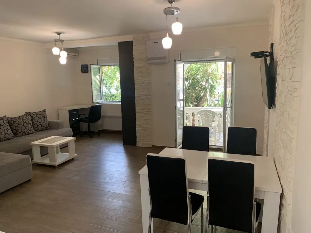 Living-dining room with gray sofa, black chairs, open balcony door
