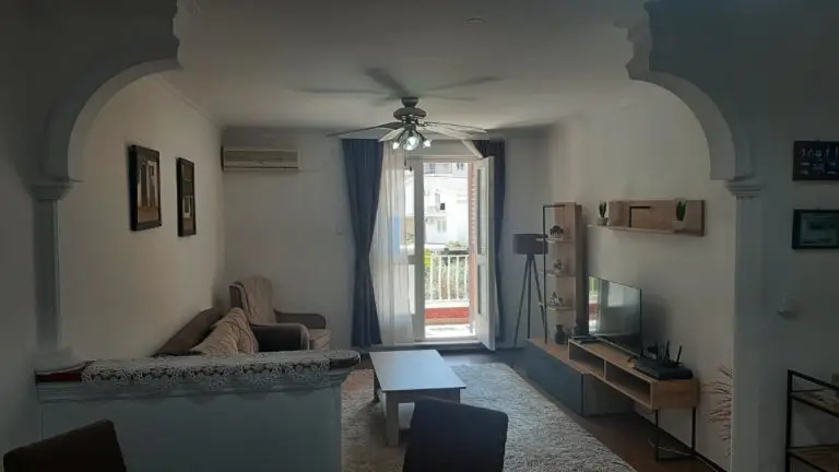 Living room with sofa, TV, coffee table, and balcony doors