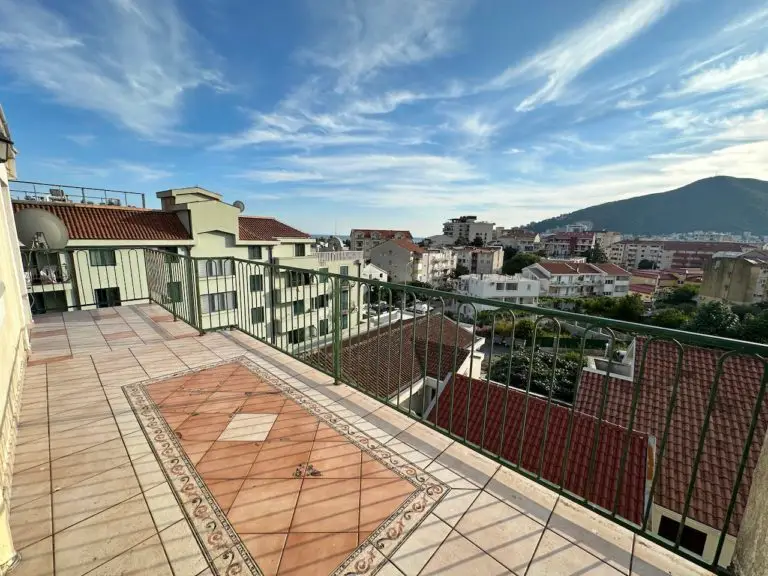 Spacious tiled balcony with green railing and city view