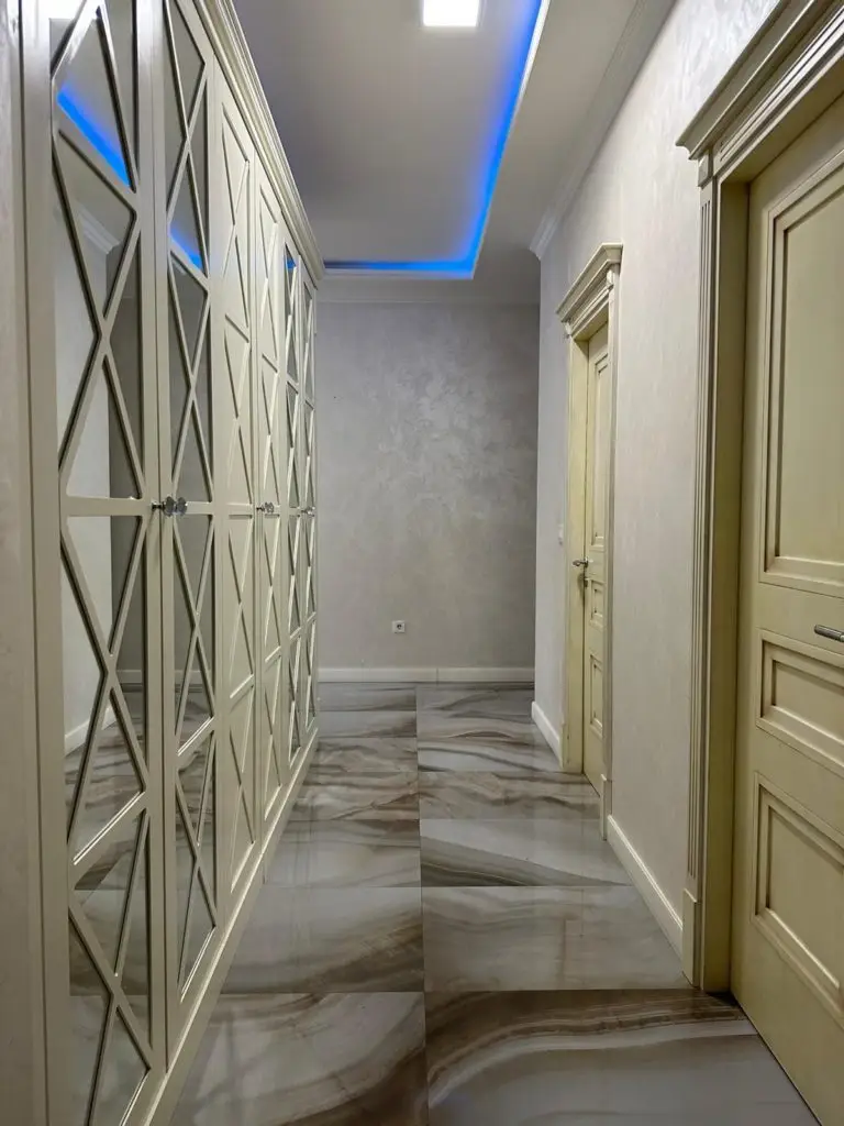 Elegant hallway with mirrored wardrobe, doors, and marble tile floor