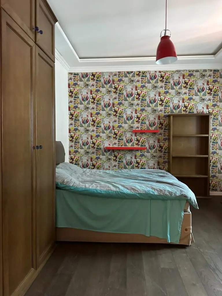 Bedroom with bed, wooden wardrobe, shelf, and comic wallpaper
