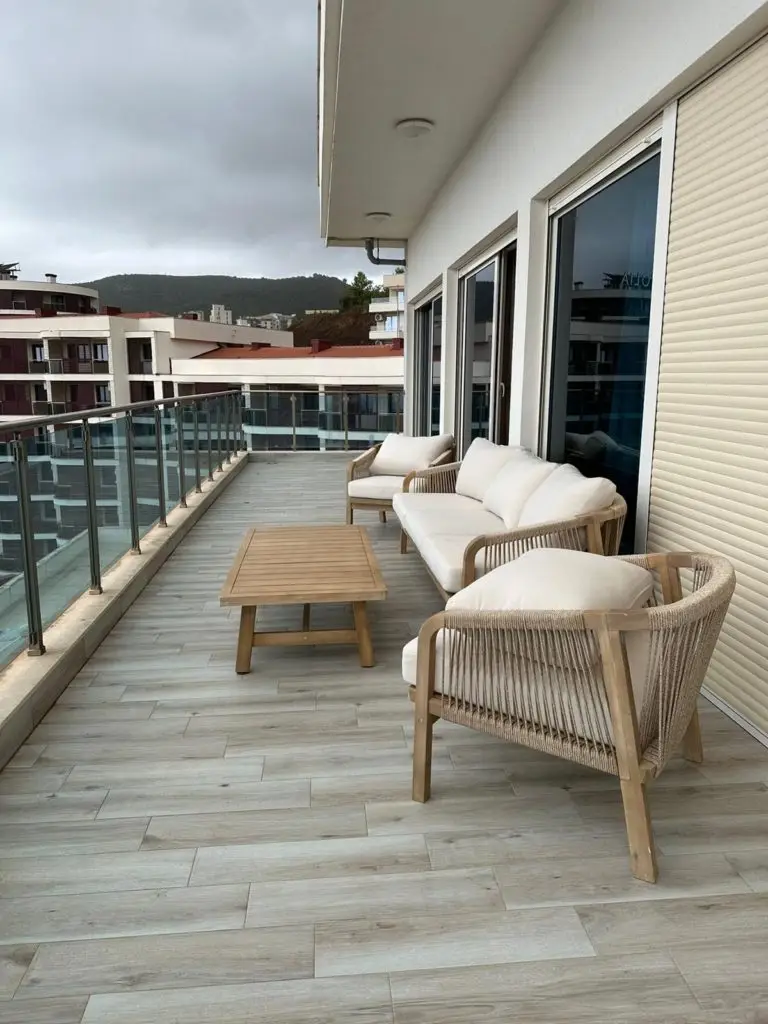 Spacious balcony terrace with wicker seating and wooden table