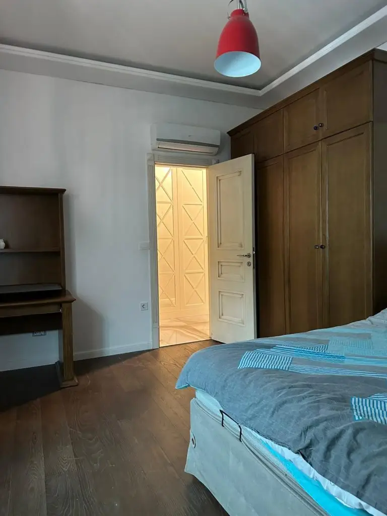 Bedroom with bed, wardrobe, desk, and open door to lit hallway