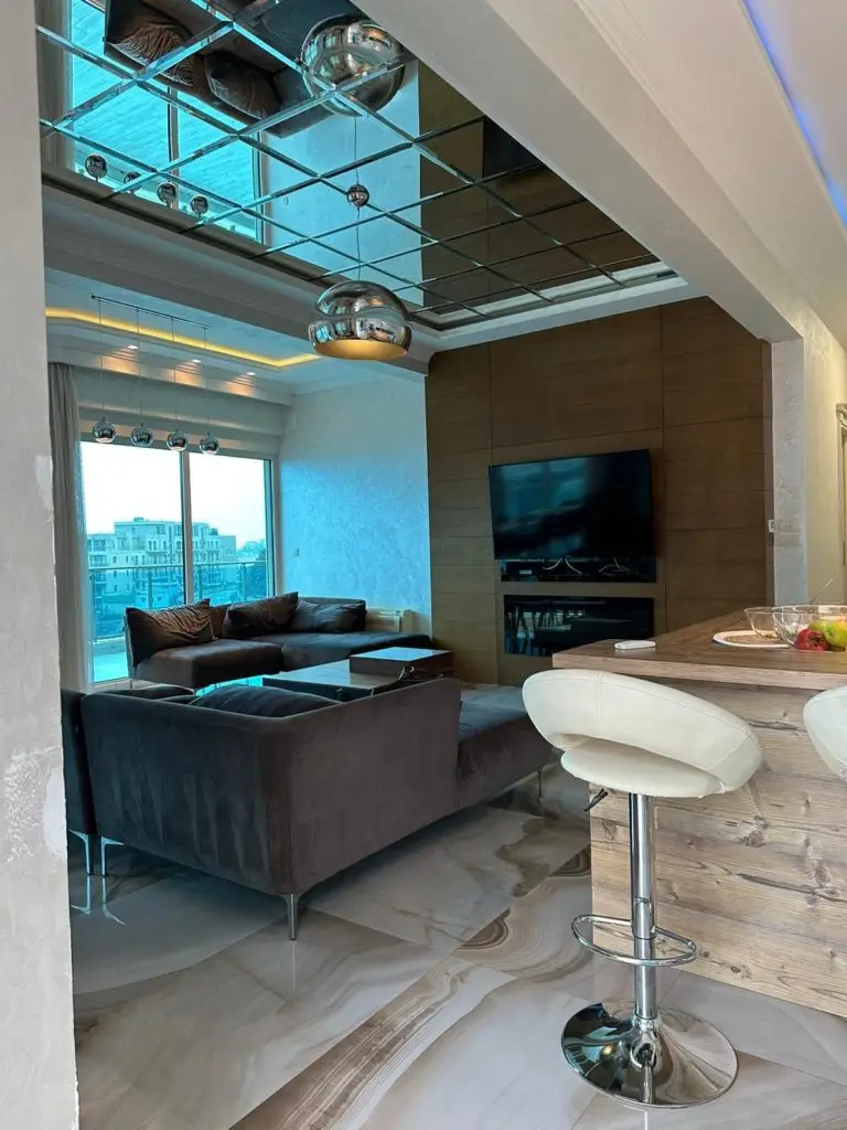 Modern penthouse living room with mirrored ceiling and kitchen bar