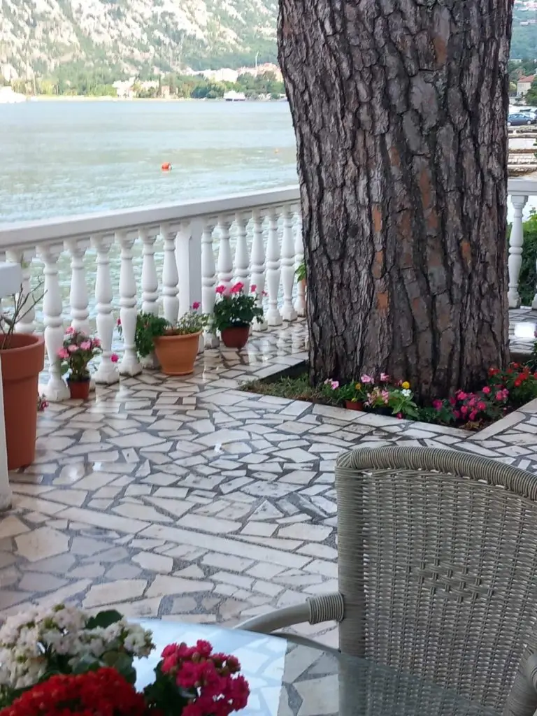 Stone patio by the water with potted flowers and railing