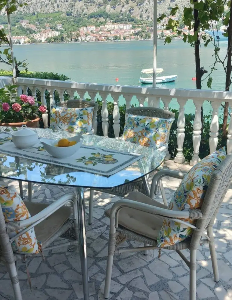Outdoor table and chairs overlooking a bay with a small boat