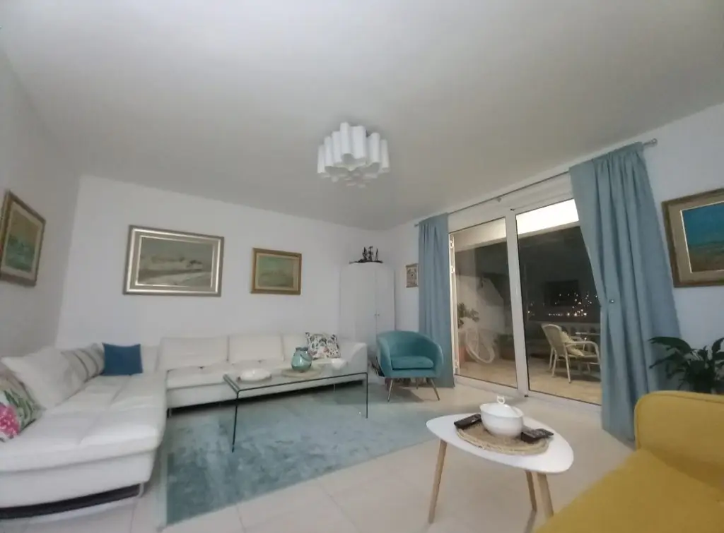 Bright living room with white sectional, blue chair, and sliding glass doors