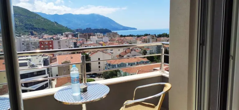 Balcony with table, chair, water bottle, sea and mountains