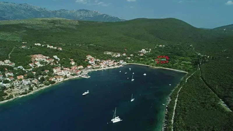 Aerial view of a coastal bay with boats, town, and green hills