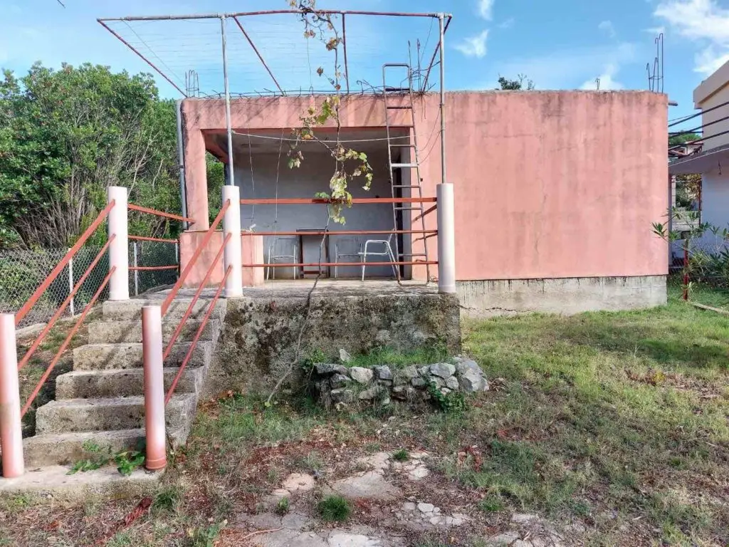 Unfinished pink house with stairs, porch, and ladder