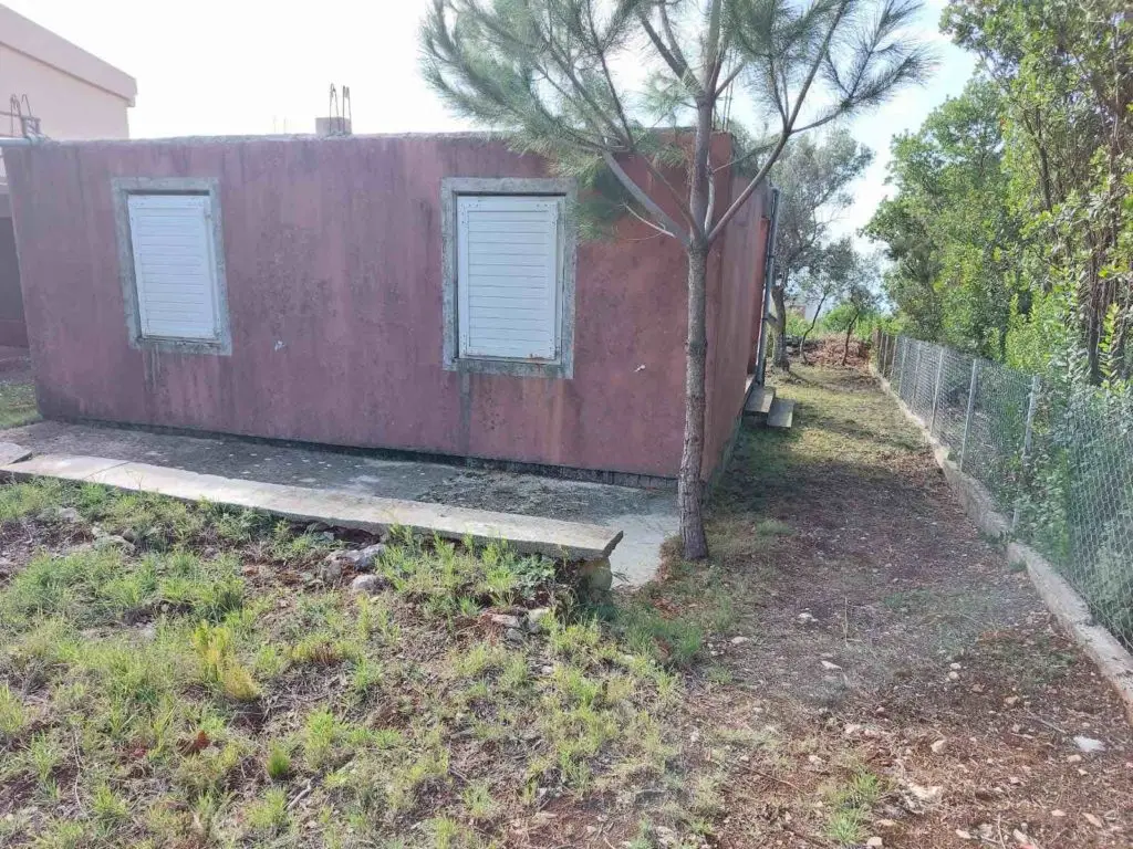 Pink house side with two white shuttered windows and dirt path