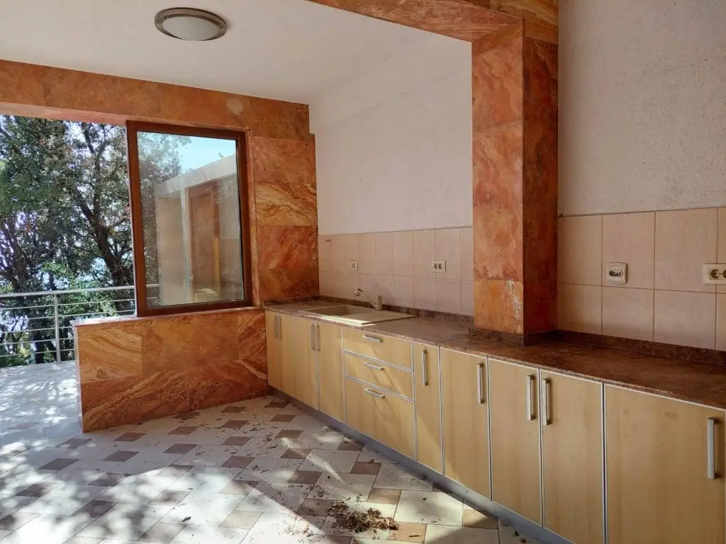 Outdoor kitchen with cabinets, sink, and balcony view