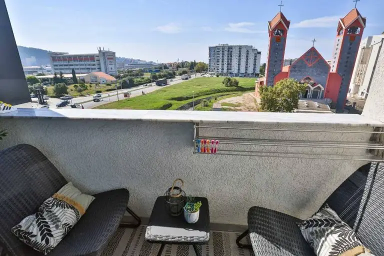Balcony with two chairs, small table, and city view