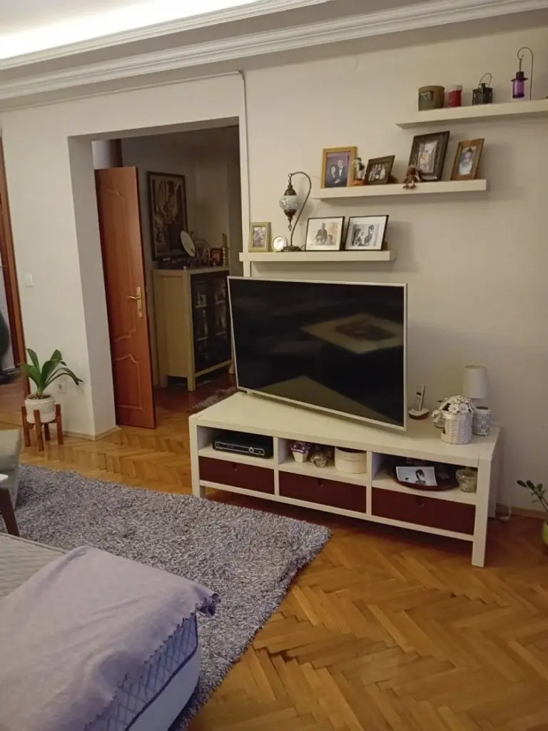 Living room with TV on white stand and floating shelves