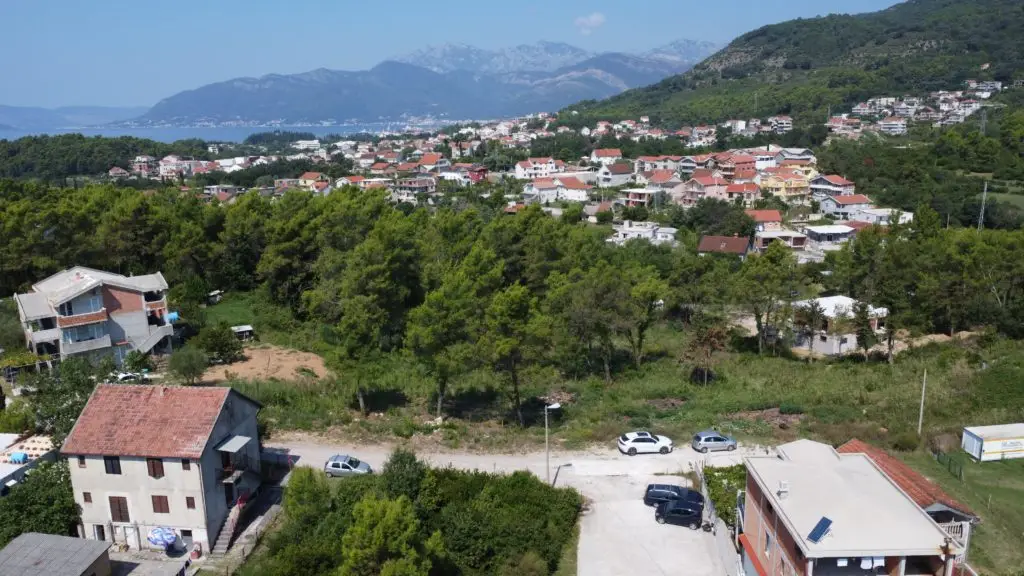 Aerial view of hillside town with sea and mountains in background