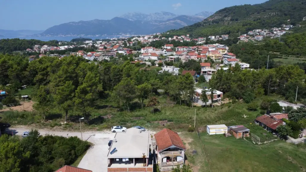 Aerial view of houses, trees, sea, and mountains