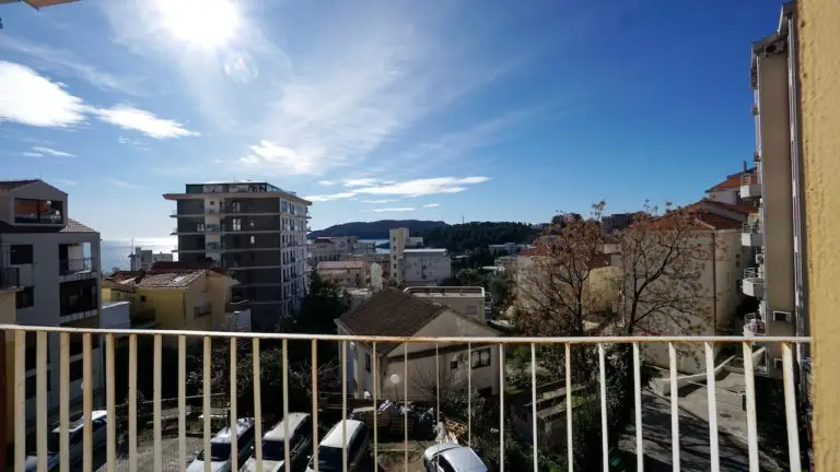 Balcony view of apartment buildings and sea under blue sky