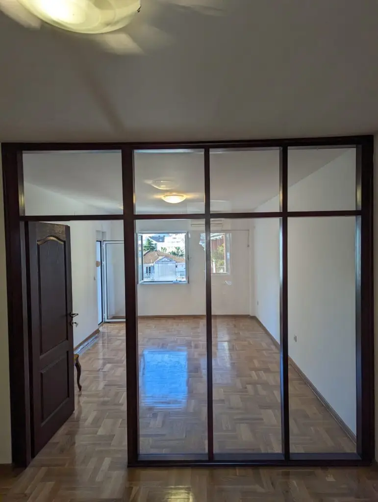 Empty room with parquet floor and glass partition door