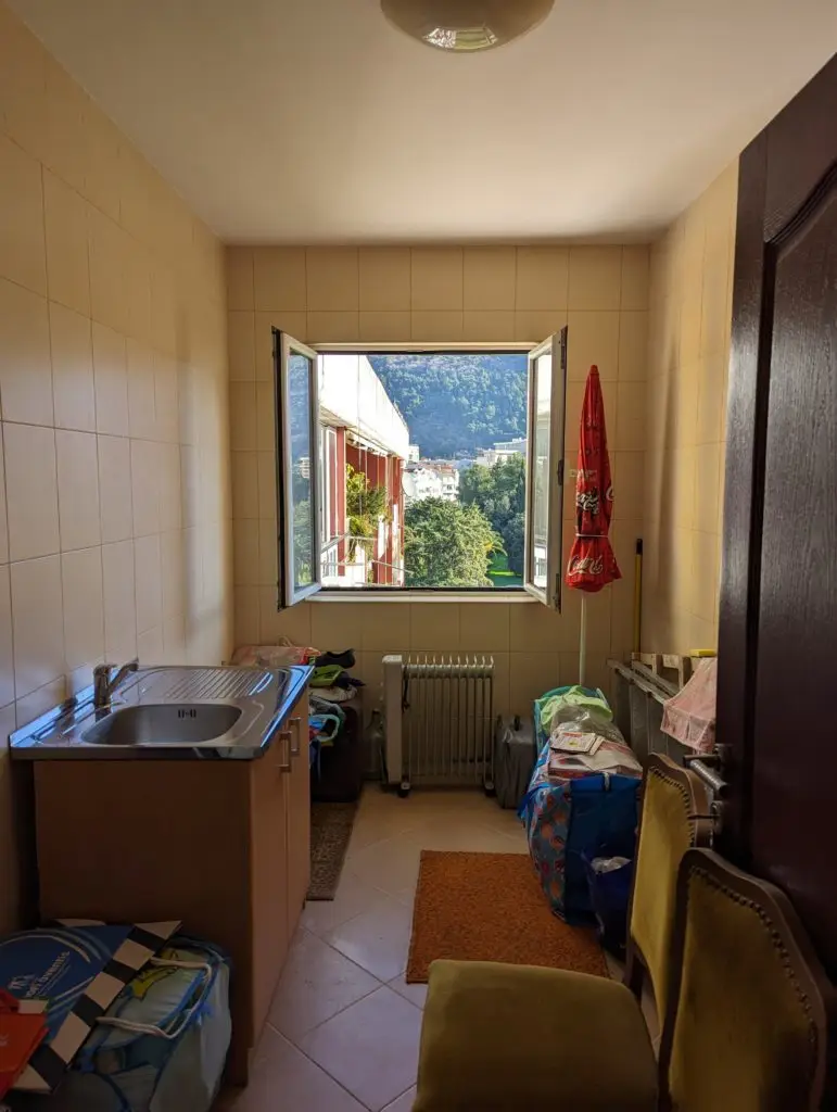 Narrow tiled kitchen with open window and mountain view