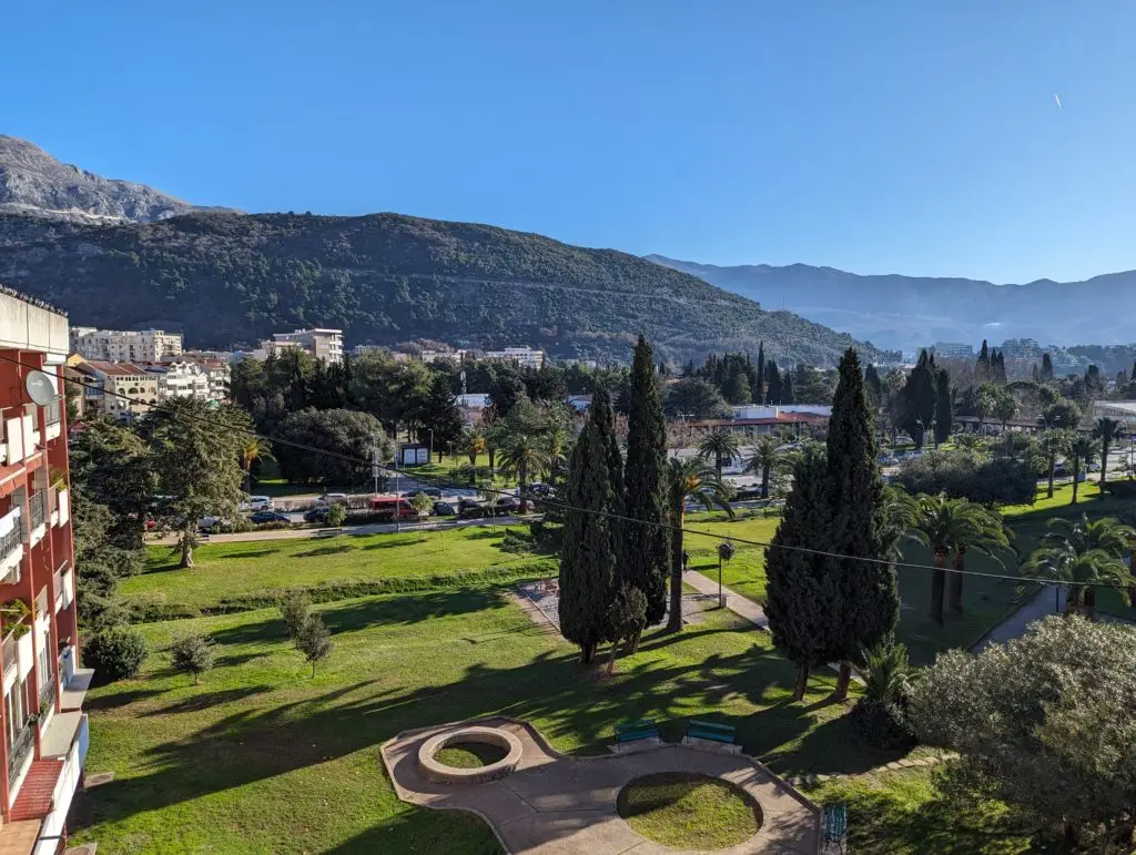 View over a green park with cypress trees and mountains