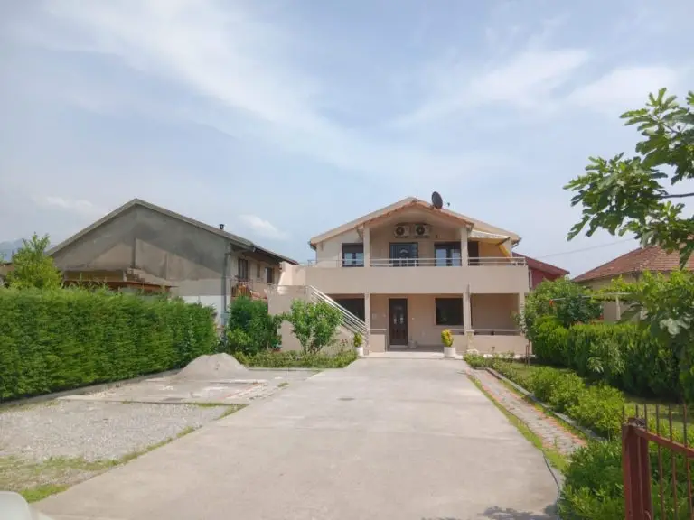 Two-story beige house with driveway and garden
