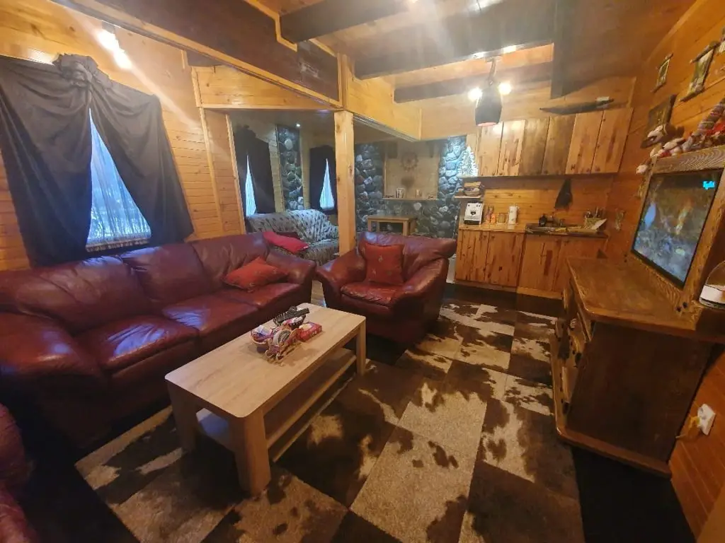 Cozy wooden cabin living room with burgundy sofa and armchair