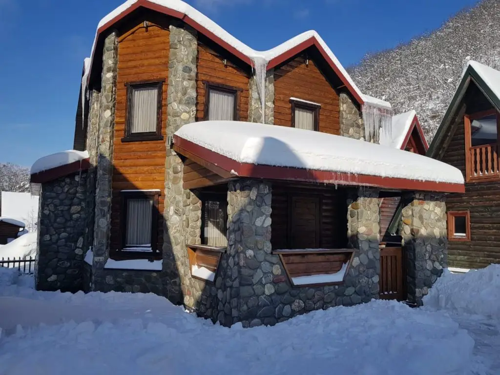 Snow-covered stone and wood chalet house in mountains