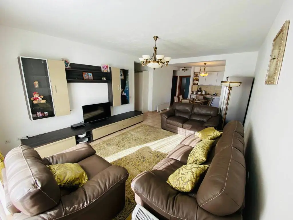 Living room with brown leather sofas, TV unit, and chandelier