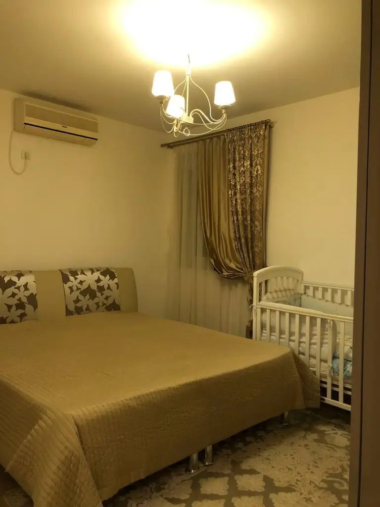Bedroom with bed, crib, chandelier, and wall-mounted air conditioner