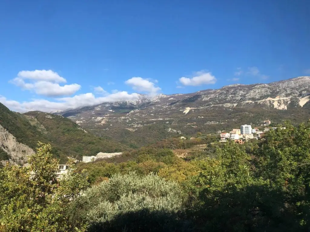 Mountain valley with trees and scattered buildings under blue sky