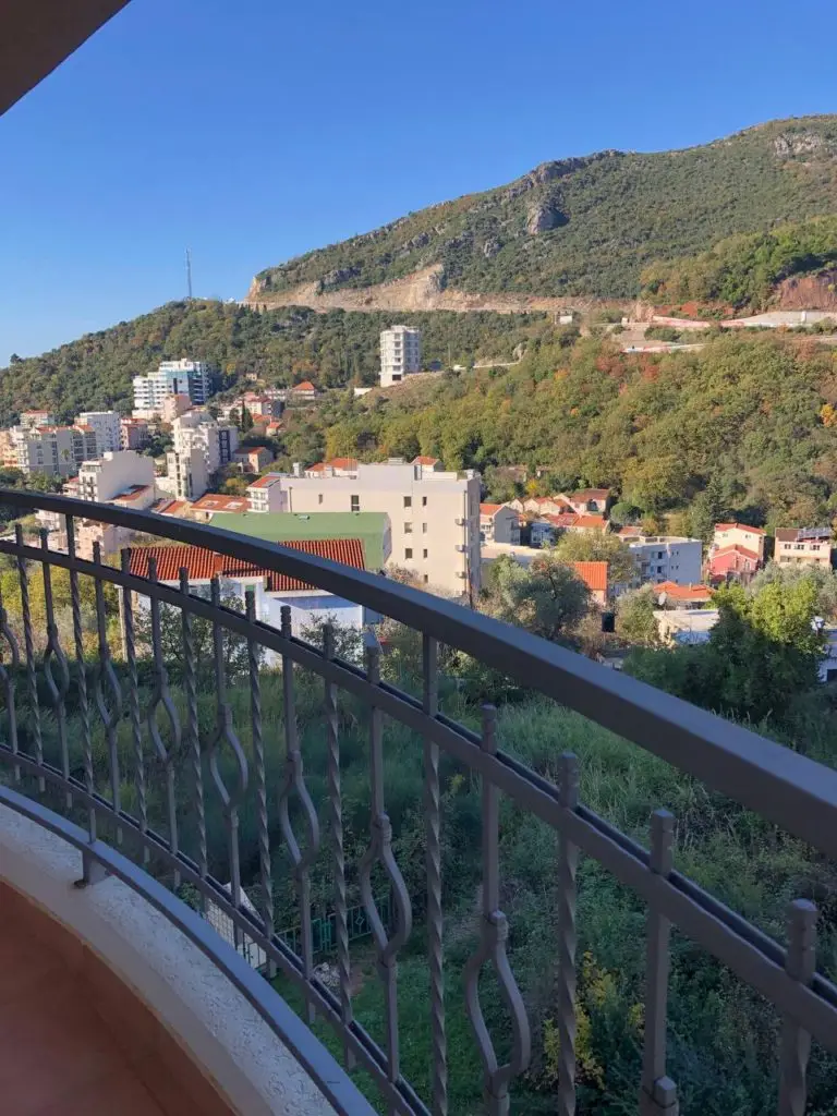 Balcony railing overlooking hillside buildings and blue sky