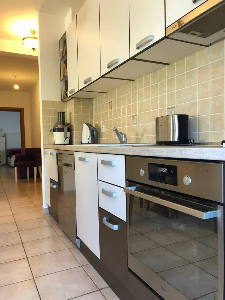 Modern kitchen with white cabinets, tiled backsplash, and built-in oven