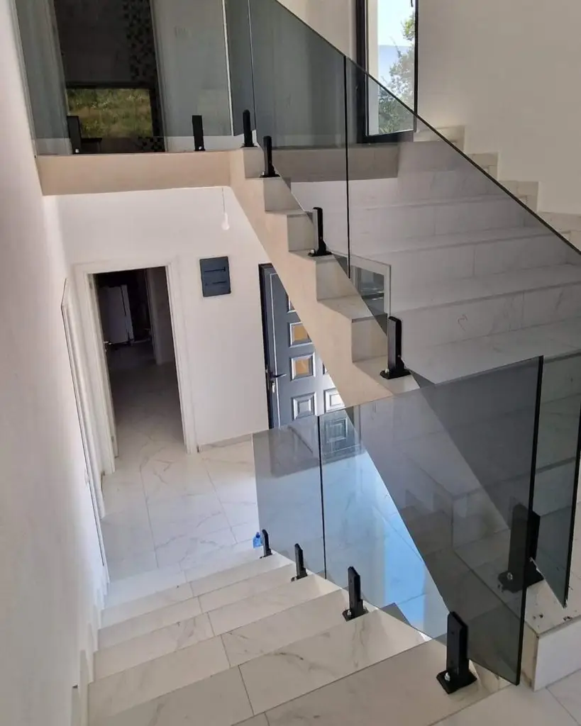 Modern white staircase with glass railings in a house interior