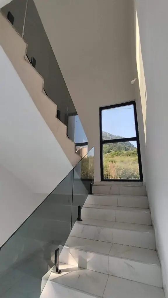 Modern staircase with glass railing and large window view