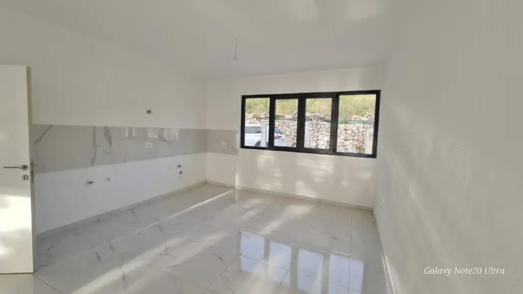 Empty white tiled room with black-framed window and door