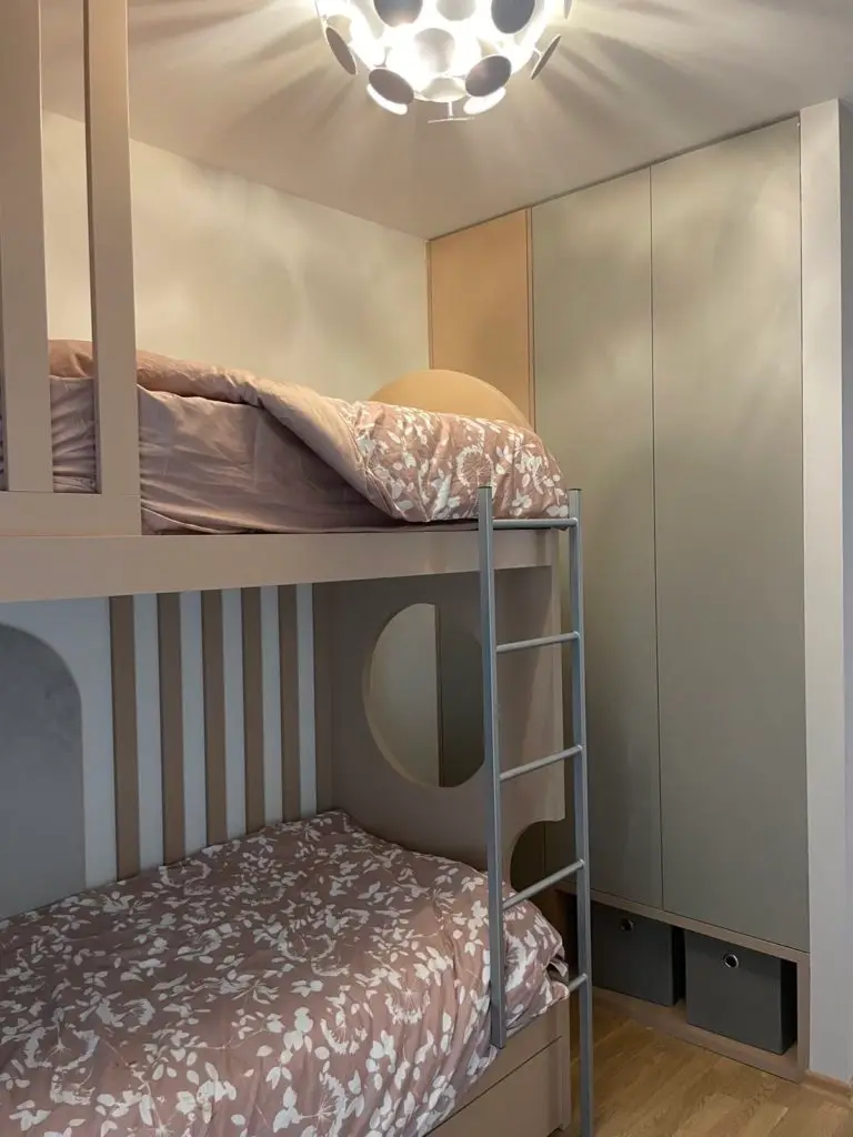 Built-in bunk bed with pink floral bedding and wardrobe cabinetry