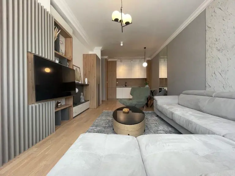 Modern living room with gray sofa, TV, and kitchen view