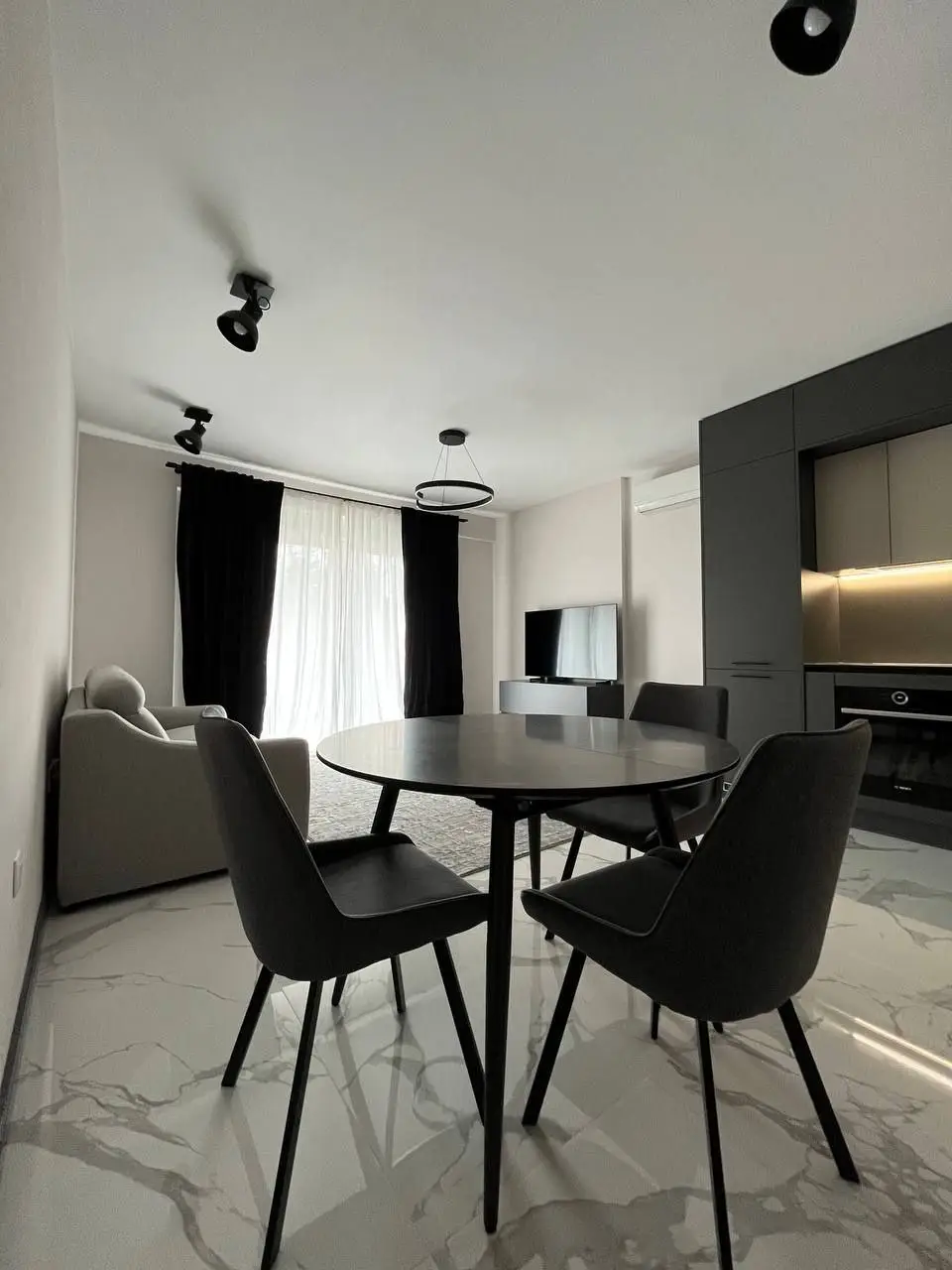 Modern dining area with round table, black chairs, and sofa