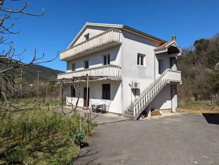 White two-story house with balconies and exterior stairs