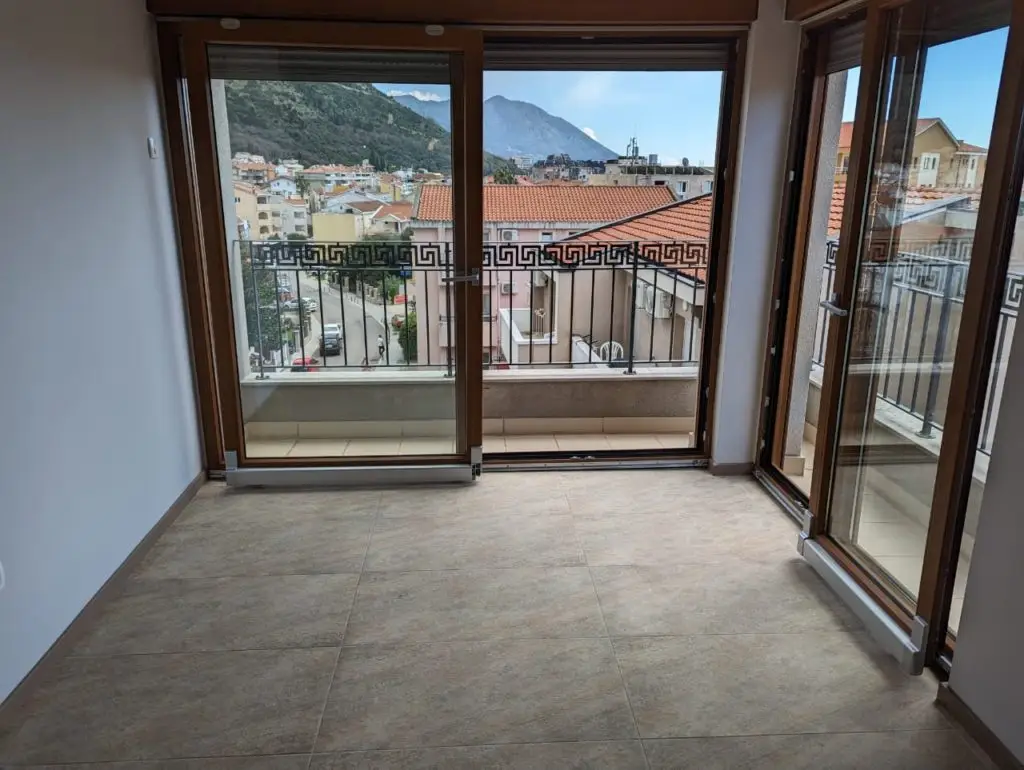 Empty room with tiled floor and glass balcony doors overlooking mountains
