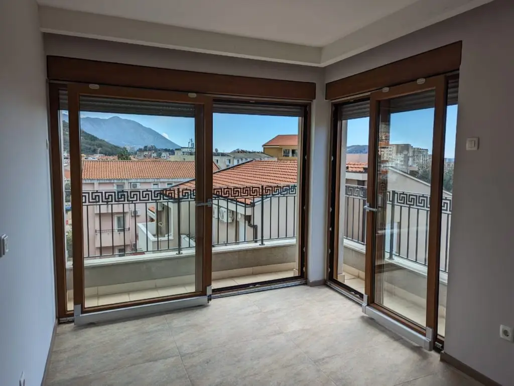 Empty room with corner balcony doors and mountain view