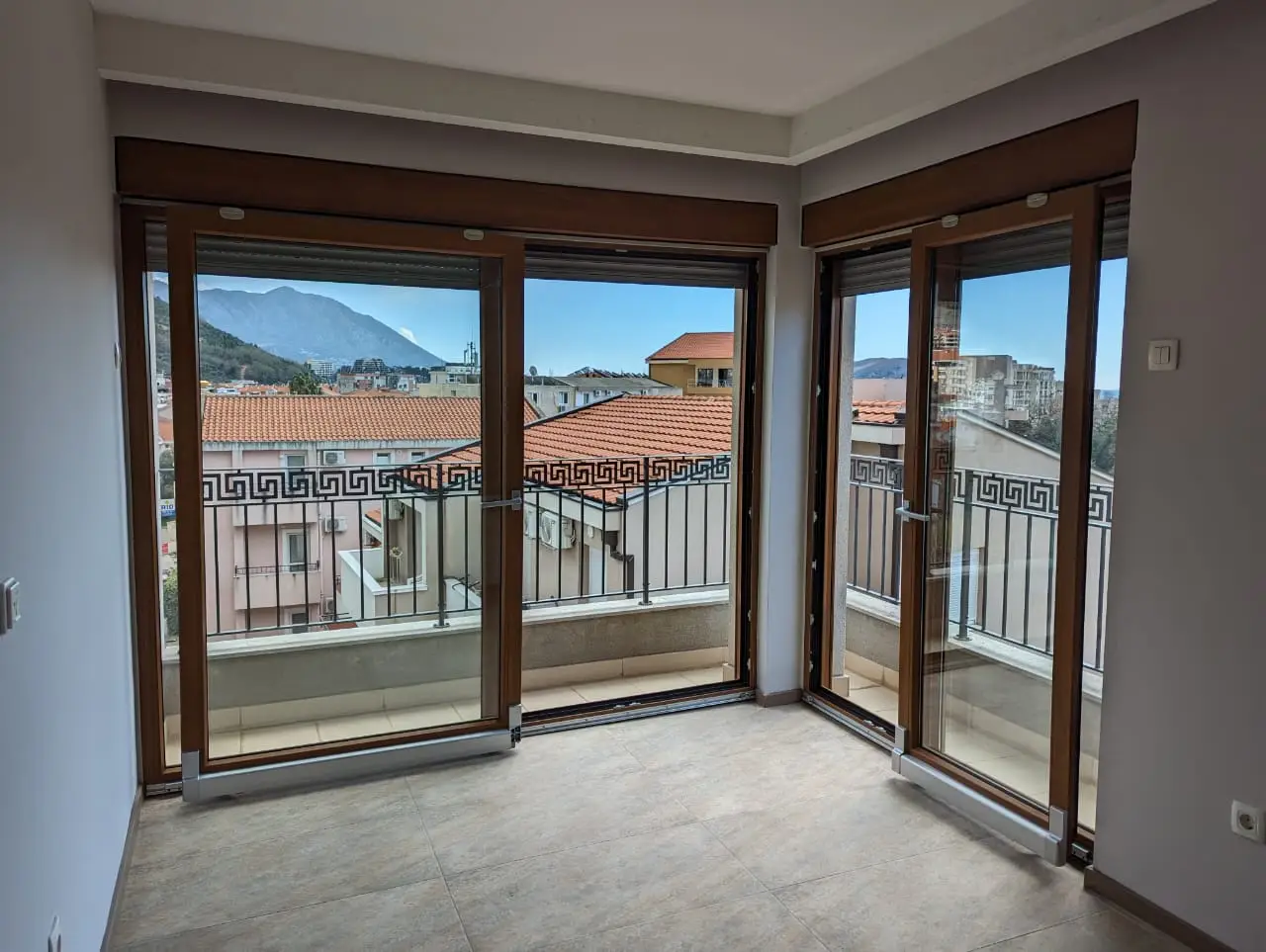 Empty room with corner balcony doors and mountain view