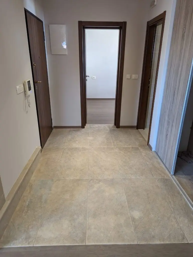 Tiled apartment hallway with brown doors and white walls