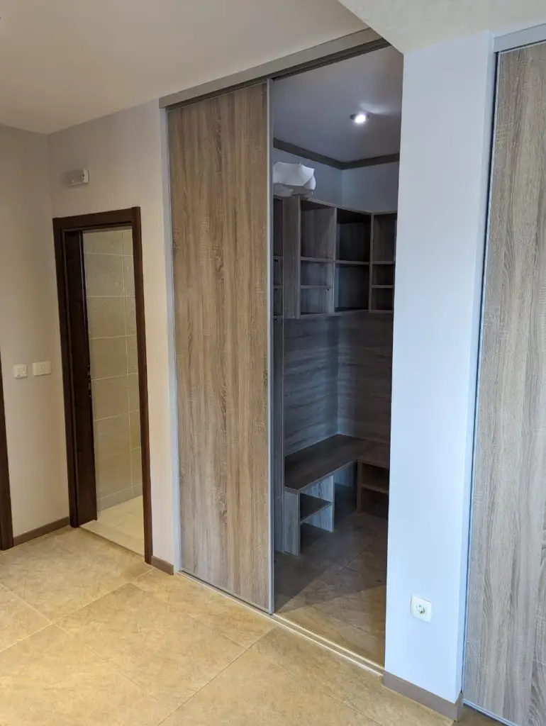 Built-in wood wardrobe beside tiled doorway in room