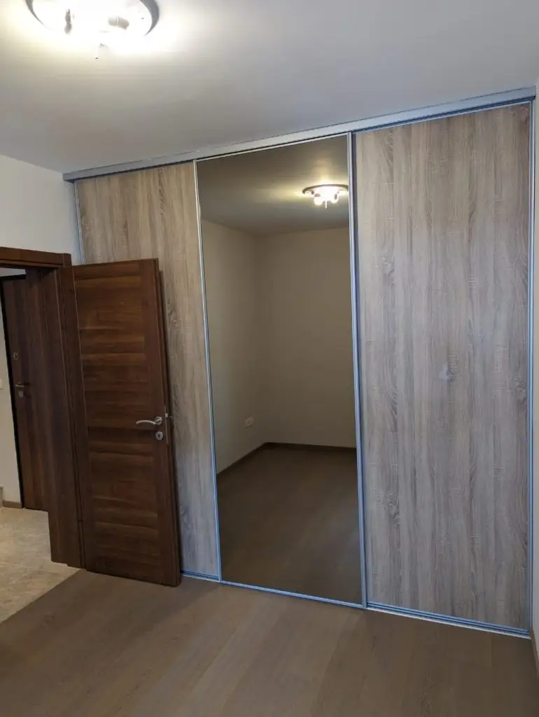 Bedroom with mirrored sliding wardrobe and open wooden door