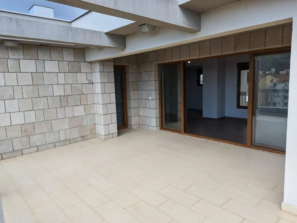 Large tiled terrace with sliding glass doors and stone walls