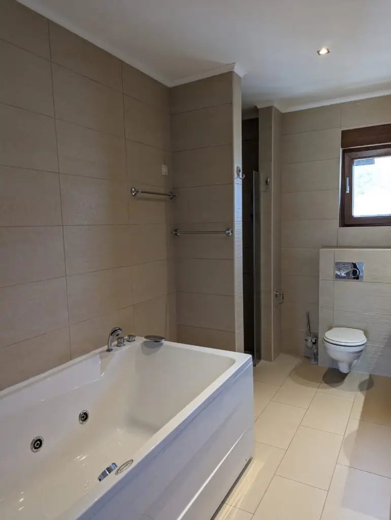 Modern beige bathroom with bathtub, toilet, and window